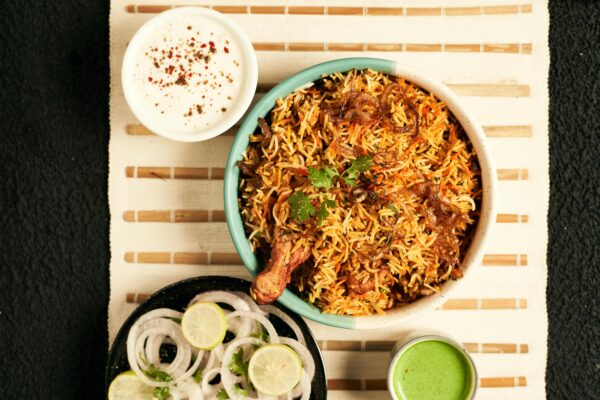 A flavorful bowl of Indian chicken biryani served with raita and onion salad, perfect for an aromatic meal.